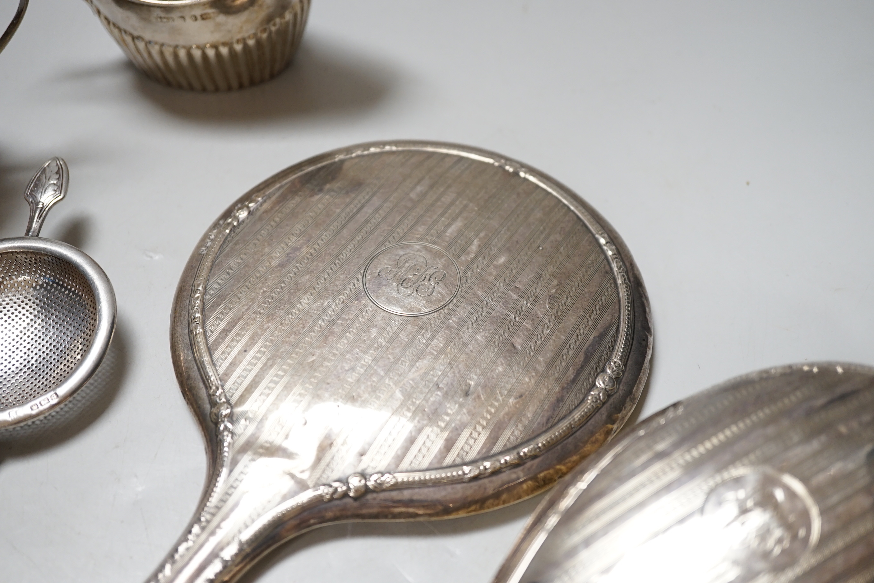 A late Victorian silver bachelor's cream jug with matching sugar bowl, Birmingham 1892, 160 grams, a George V tea strainer, 47 grams and a silver mounted hair brush and hand mirror